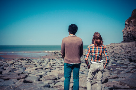 A couple is standing on the beach and looking at the seaの写真素材