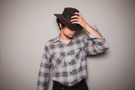 A young man wearing a cowboy hat and a plaid shirt is posing against a green wallの写真素材