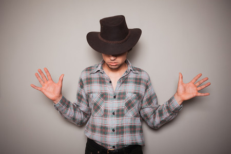 A young cowboy wearing a plaid shirt is posing against a green wallの写真素材