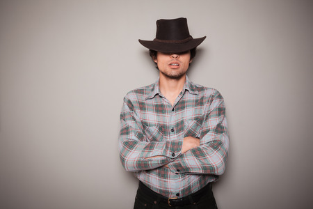 A young man wearing a cowboy hat and a plaid shirt is posing against a green wallの写真素材