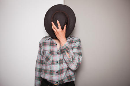 A young cowboy is standing a against a green and white の写真素材