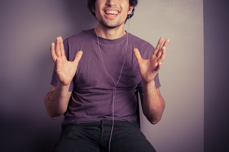 A happy young man is listening to music through his earphonesの写真素材