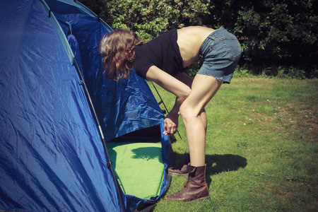 A young woman is standing outside a tent and looking inの写真素材