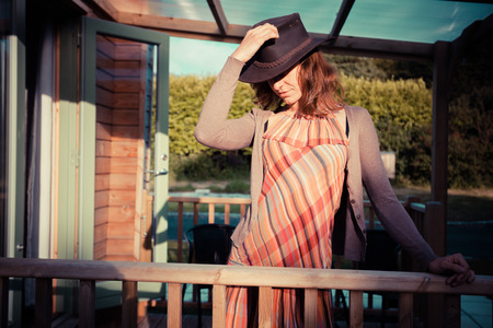 A young woman wearing a cowboy hat is standing on the porch of a cabinの写真素材