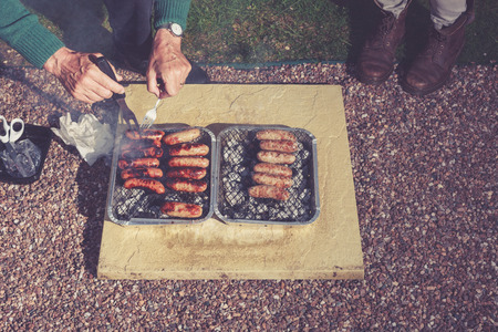 Two people are cooking meat on a barbecue at nightの写真素材
