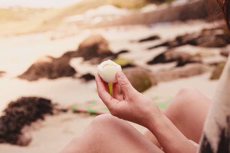 A young woman is holding an egg in her hand on the beach