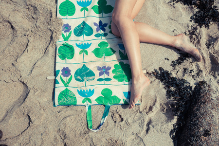 A young woman is relaxing and sunbathing on the beachの写真素材