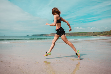 A young woman is running on the beachの写真素材