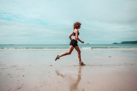 A young woman is running on the beachの写真素材