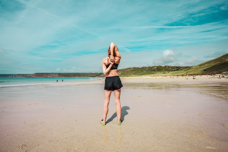 A fit young woman is stretching her arms on the beachの写真素材
