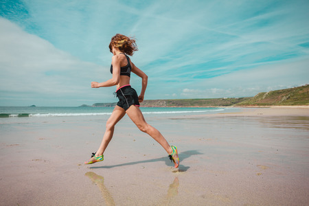 A young woman is running on the beachの写真素材