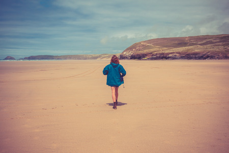 A young woman is walking on the beach by herselfの写真素材