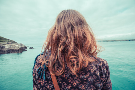 A young woman is sitting by the water's edge in a harbourの写真素材