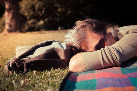A young woman is relaxing on a blanket at sunset in a parkの写真素材