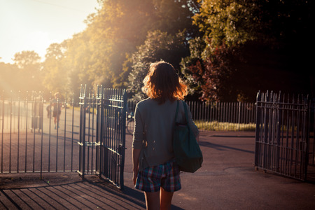 A young woman is walking into the sunset in a parkの写真素材