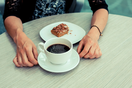 A young woman is having coffee and cake by the window in an airportの写真素材