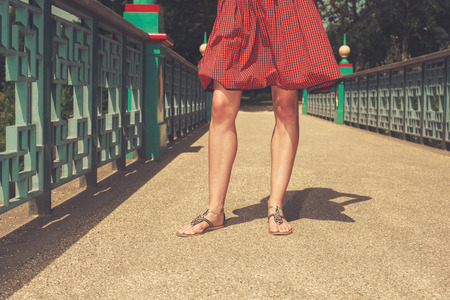 The legs of a young woman standing on a bridge in a park on a summer dayの写真素材