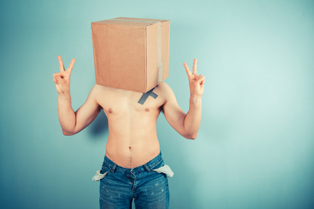 A young man with a cardboard box on his head is displaying a victory signの写真素材