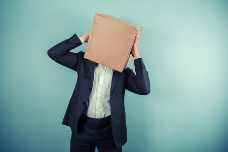 A businessman with a cardboard box on his head has a headacheの写真素材