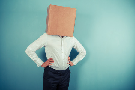 A man is standing around with a cardboard box on his headの写真素材