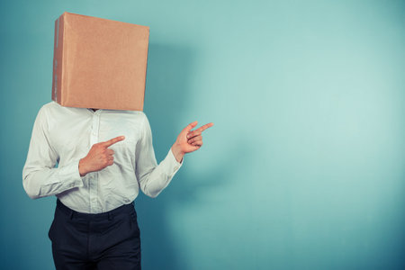 A man with a cardboard box on his head is pointingの写真素材