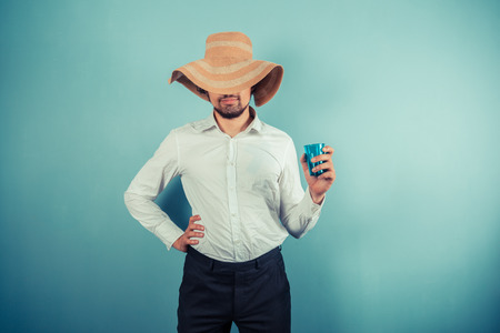 A young man wearing a beach hat is holding a glassの写真素材