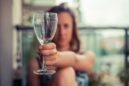 A young woman is sitting outside with a glass of wineの写真素材