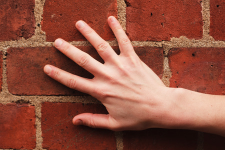 A young woman s hand touching a red brick wallの写真素材