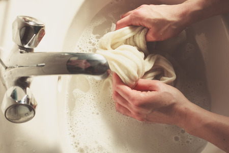 A woman is washing woolen socks in a sinkの写真素材