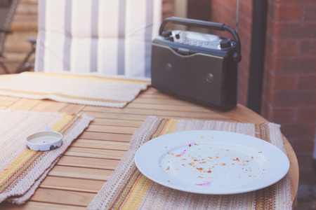 A radio and a plate with leftovers from breakfast on a table in a garden outside at sunriseの写真素材