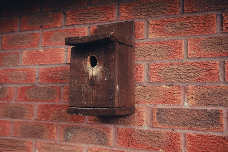 A wooden bird house on a red brick wallの写真素材