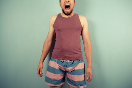 A young man in striped shorts is pulling silly facesの写真素材