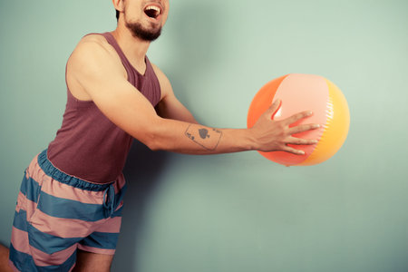 A young man is catching a beach ball