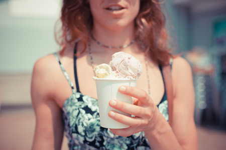 A young woman is eating ice cream on the beachの写真素材