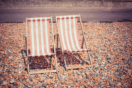 Two deck chairs on a pebble beachの写真素材