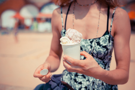 A young woman is eating ice cream on the beachの写真素材