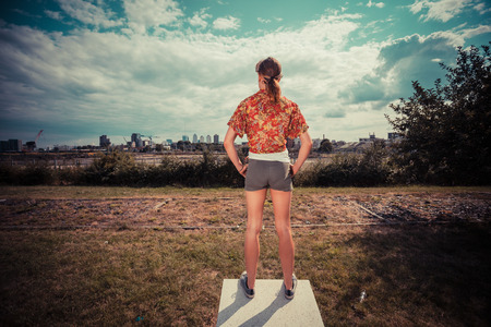 Rear view of a young woman standing outside on a sunny dayの写真素材