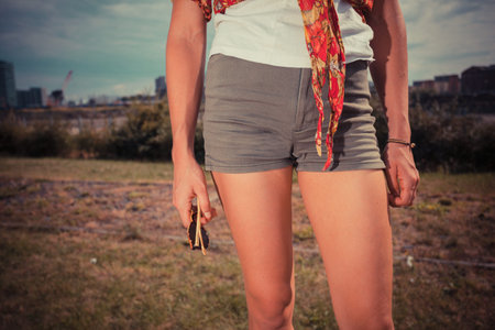 A young woman wearing short shorts is standing outsideの写真素材