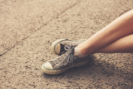 The feet and legs of a young woman sitting in the streetの写真素材