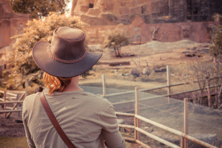 A young woman is standing by an animal enclosureの写真素材