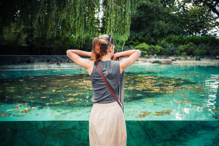 A young woman is standing by a large tank of waterの写真素材