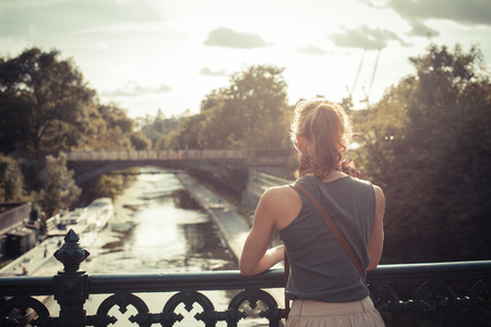 A young woman is admiring the sunset from a bridge by a canalの写真素材
