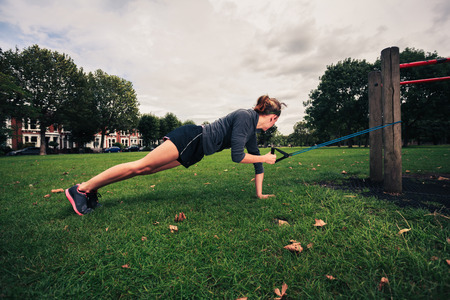 A young woman is exercising and working out with a resistance band in the parkの写真素材