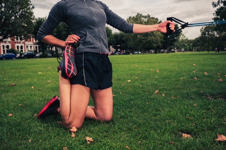 A young woman is exercising and working out with a resistance band in the park