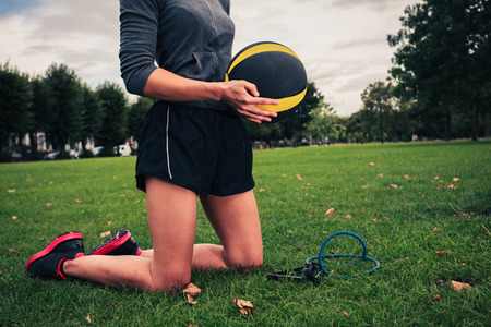A young woman is in the park with a medicine ball and a resistance bandの写真素材