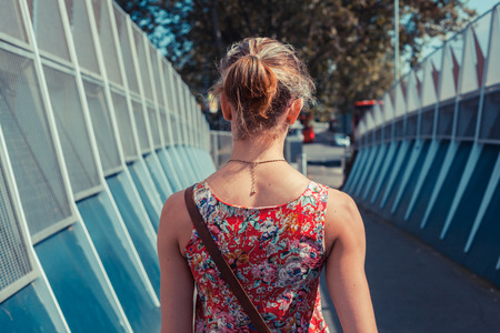 A young woman is walking in the street on a summerの写真素材