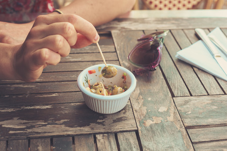 Close up on a woman picking olives from a bowlの写真素材