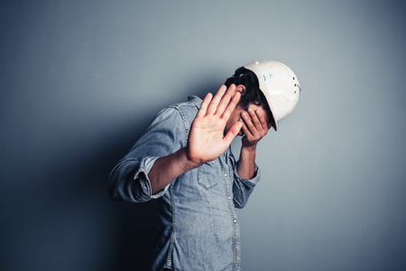 An ashamed blue collar worker is hiding his faceの写真素材