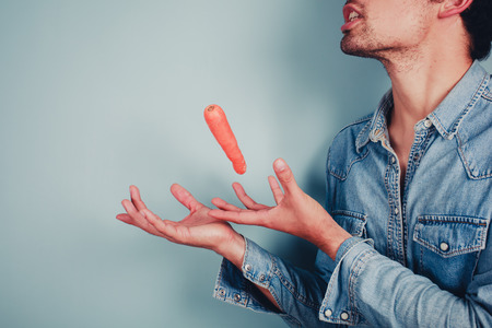 A young man is using magic to make carrot levitateの写真素材