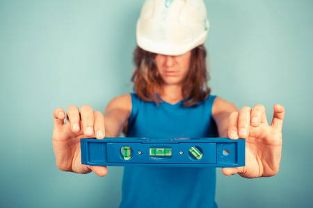 A young female buidler is holding a levelの写真素材